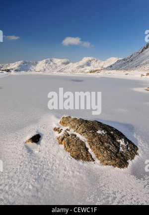 Rock und gefrorenen drei Bergseen auf Nordwestgrat mit Schnee bedeckten Scafell und Scafell Pike im Hintergrund, im winter im Lake District Stockfoto