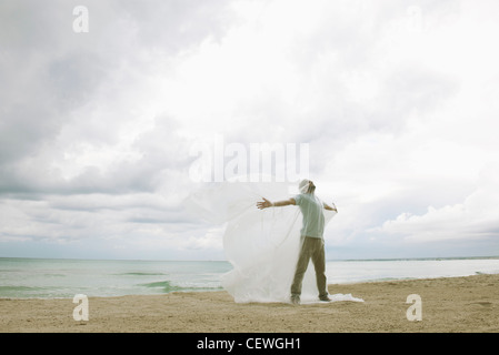 Mann gefangen in Plastik am Strand Stockfoto