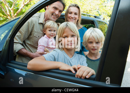 Familie posiert neben Auto, auf der Suche durch offene Fenster, Porträt Stockfoto