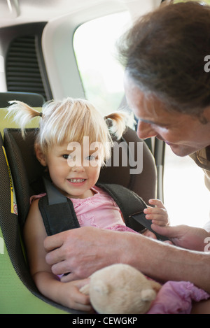 Vater, die Mädchen in Autositz befestigen Stockfoto