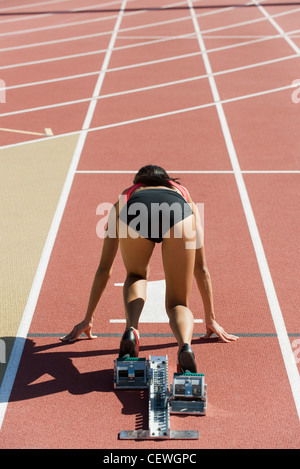 Frau kauerte in Startposition auf Laufstrecke, Rückansicht Stockfoto