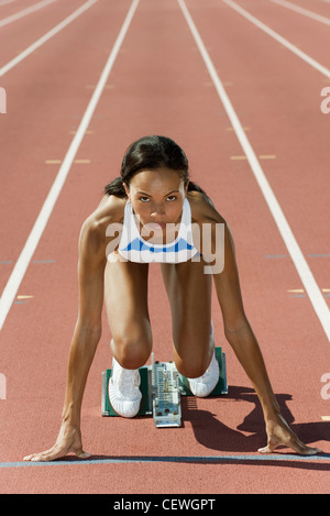 Frau kauerte in Startposition auf Laufband Stockfoto