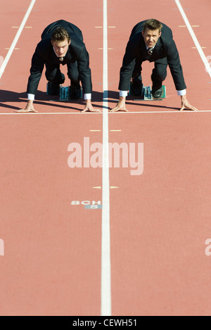 Geschäftsleute kauerte in Startposition auf Laufband Stockfoto