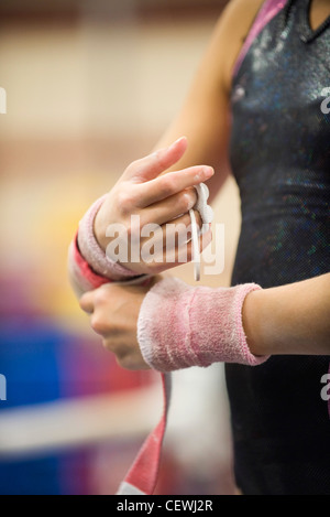 Weiblicher Gymnast Umhüllung Handgelenke in Vorbereitung, beschnitten Stockfoto