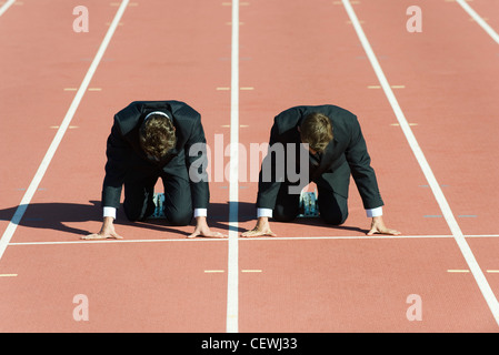 Geschäftsleute kauerte in Startposition auf Laufband Stockfoto