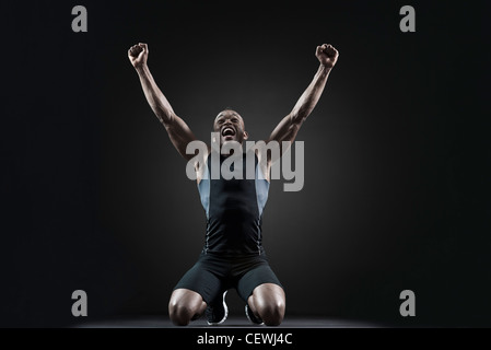 Männlicher Athlet schreien mit erhobenen Armen Stockfoto