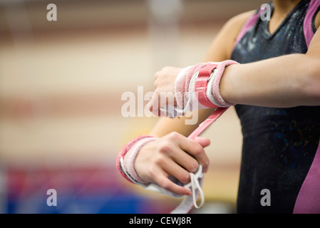 Weiblicher Gymnast Umhüllung Handgelenke in Vorbereitung, beschnitten Stockfoto