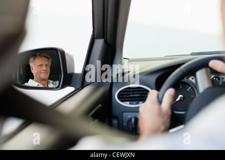 Mann, Steuerwagen, spiegelt sich in der Fahrer Außenspiegel Stockfoto