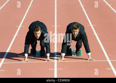 Geschäftsleute kauerte in Startposition auf Laufband Stockfoto