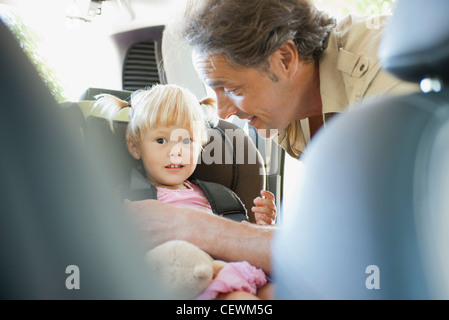 Vater, die Mädchen in Autositz befestigen Stockfoto