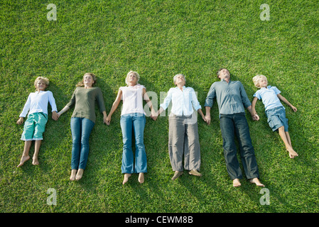 Gruppe liegen nebeneinander auf dem Rasen, die Hand in Hand Stockfoto