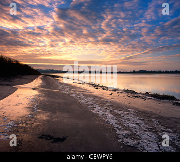 Ein Sonnenaufgang Himmel spiegelt sich im Wasser und eisigen Ufer des Flusses Severn. Stockfoto