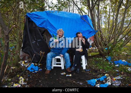 Zwei "unten und outs' trinken billigen Wein und Lager in einem provisorischen Zelt in einen stillgelegten Clyde Dockyard, Glasgow lebt. Stockfoto