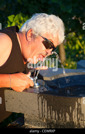 Reifer Mann trinken von Wasser-Brunnen Stockfoto