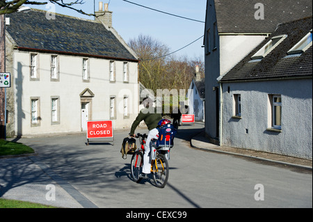 Mann mit Kind reiten vorbei an Straße gesperrt-Schild. Flutung des River Spey in Garmouth, Schottland im April 2010 wegen schweren Schnee schmelzen. Stockfoto