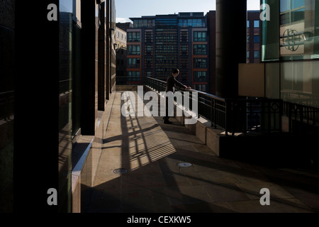 Eine Stadt-Büroangestellte hält während einem anstrengenden Tag für einen ruhigen Moment Frieden mit einer Zigarette in einer Seitenstraße London. Stockfoto