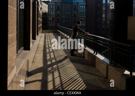 Eine Stadt-Büroangestellte hält während einem anstrengenden Tag für einen ruhigen Moment Frieden mit einer Zigarette in einer Seitenstraße London. Stockfoto