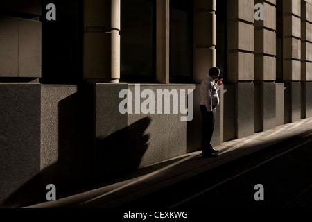 Eine Stadt-Büroangestellte hält während einem anstrengenden Tag für einen ruhigen Moment Frieden mit einer Zigarette in einer Seitenstraße London. Stockfoto