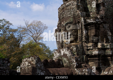 Blick nach oben auf die massiven steinernen Gesichter clustering rund um den zentralen Gipfel innerhalb der komplexen Angkor Thom Stockfoto