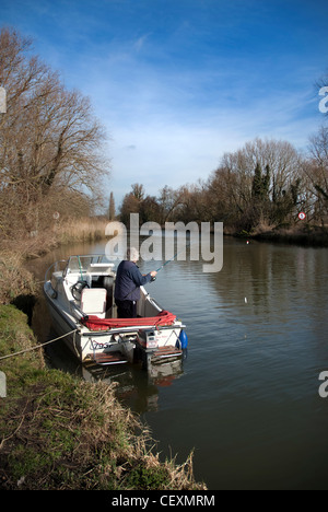 älterer Mann Angeln vom Boot auf Fluß Waveney bei Geldeston Norfolk uk Stockfoto