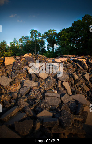 Baustelle. Einfache, saubere vertikale Farbfoto. Haufenweise Kies, Asphalt, mit Bäumen im Hintergrund, blauer Himmel gebrochen. Stockfoto