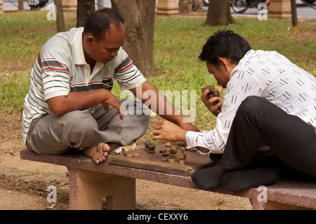 Zwei barfuß auf einer konkreten Bank sitzen Männer spielen Schach in den Gärten des Wat Phnom, der Haupttempel und Namensgeber von Phnom Penh Stockfoto