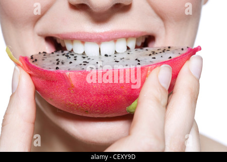 Weibchen tragen rosa Lipgloss, Essen einen Keil der Drachenfrucht Stockfoto