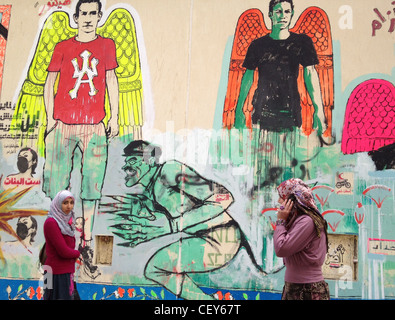 Ägyptische Frauen zu Fuß vor einem pro-Revolution Wandgemälde neben dem Tahrir auf der AUC Wand Kairo Ägypten Stockfoto
