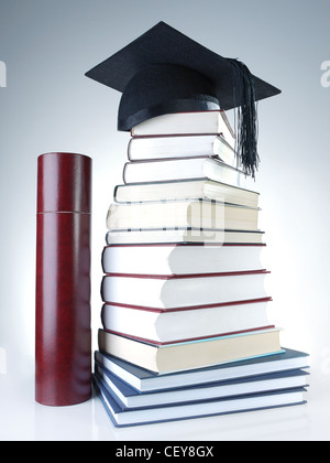 Schwarze Graduierung Kappe auf Stapel Bücher mit Diplom tube Stockfoto