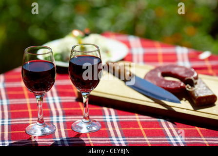 Gläser Rotwein auf einem Tisch, einige Blumen im Hintergrund Stockfoto