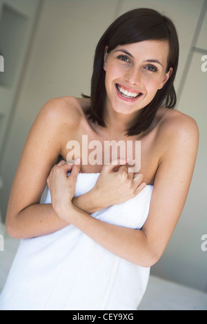 Weiblich, schulterlang direkt brünette Haare, trägt weißes Handtuch um ihr Bett stehen gewickelt Stockfoto