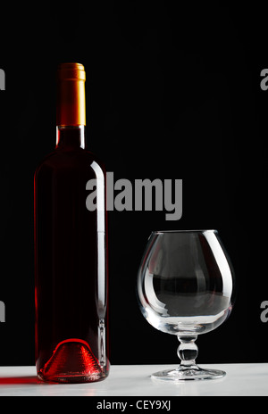 Flasche Rotwein und ein leeres Glas auf Tisch Stockfoto