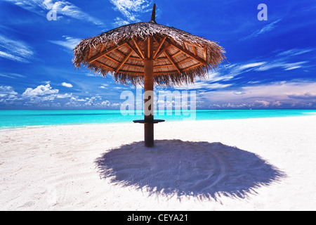 Sonnenschirm auf weißem Sand neben tropischen Lagune Stockfoto