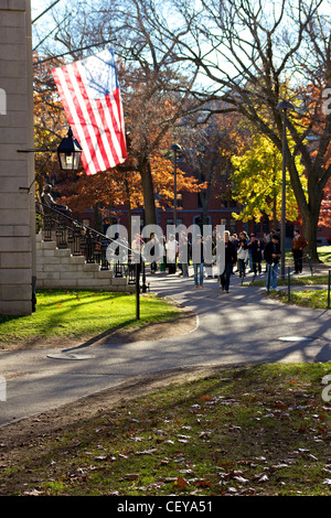 Touristen und Studenten der Harvard Universität vermischen sich im Herbst vor dem Wahrzeichen John Harvard Statue. Stockfoto