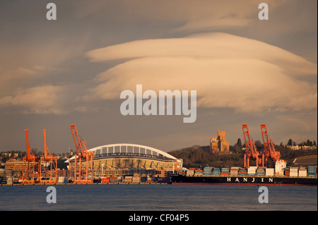 Bei Sonnenuntergang schwebt eine konische Wolke über CenturyLink Feld über Elliott Bay entlang der Uferpromenade in Seattle, Washington. Stockfoto