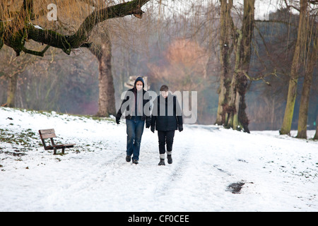Zwei Frauen zu Fuß entlang dem Schnee bedeckt Pfad in Hampstead Heath, London, England, UK Stockfoto