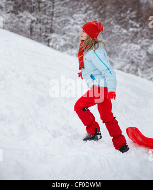 Junge Frau mit Slay, Klettern die Piste im Winter. Stockfoto