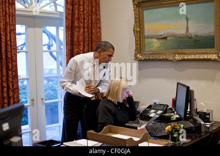 Präsident Barack Obama spricht am Telefon mit Jon Favreau, Director of Speech schreiben, beim Lesen eines Entwurfs für die Rede zur Lage der Union am persönlichen Adjutanten Anita Decker Schalter im äußeren Oval Office 23. Januar 2012 in Washington, DC. Stockfoto