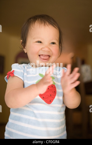 Einjähriges Mädchen lächelnd und klatschte in die Hände vor Freude. Stockfoto