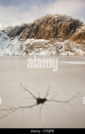 Eine gefrorene scheut Tarn mit Riss Muster in das Eis über dem Langdale Tal im Lake District, Großbritannien mit Pavey Arche Stockfoto