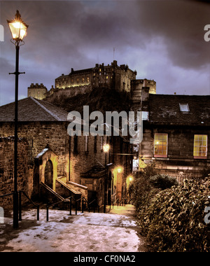 Blick auf die Winterdämmerung vom Vennel, Browns Place, Edinburgh, Blick auf Edinburgh Castle, mit Schnee auf den Steintreppen und traditioneller Straßenbeleuchtung Stockfoto