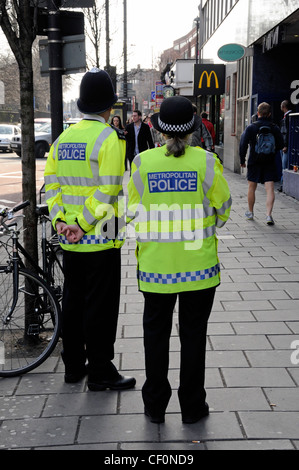 Metropolitan Police Officers, männlich und weiblich, von hinten gesehen auf Holloway Road, Islington London England UK Stockfoto