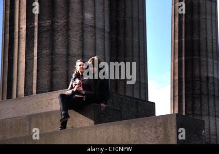 Young Lovers auf Calton Hill, Edinburgh, Lothian, Schottland, UK sitzen auf dem Neo-klassischen griechischen Stil-Denkmal Stockfoto