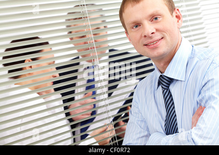 Porträt eines zuversichtlich Geschäftsmann, Blick in die Kamera, während seine Kollegen haben eine Diskussion im Hintergrund Stockfoto