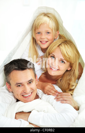 Spielerische Familie versteckt unter der Decke isoliert auf weißem Hintergrund Stockfoto