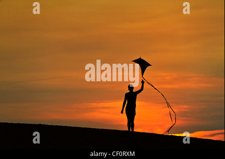 Silhouette eines Kindes einen Drachen zu fliegen. Stockfoto