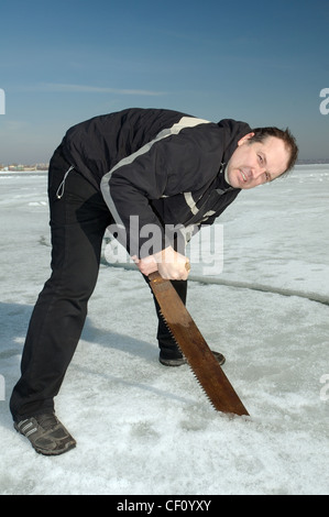 Man Sägen mit einer Hand sah eine tauchen Loch. Vorbereitungen für Subglazialen Tauchen, Eistauchen im gefrorenen Schwarzen Meer Stockfoto