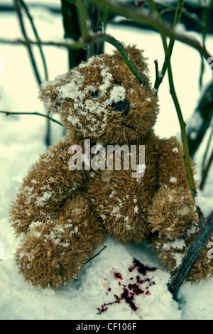 ein vergessene Teddybär im Schnee mit Blut Tropfen Stockfoto