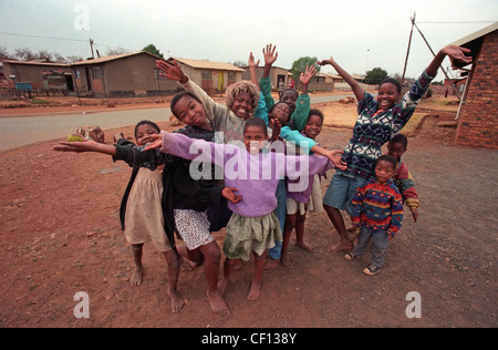 Barfuß Township-Kinder, eins das Tragen einer Perücke Marilyn Monroe geben ein herzliches Willkommen nach Soweto, Südafrika im Jahr 1996 Stockfoto