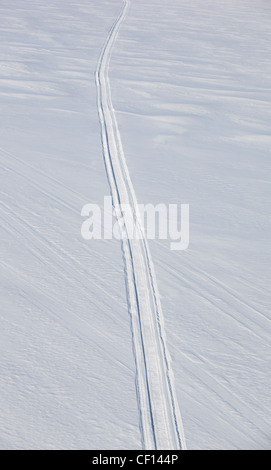 Luftbild einer einzelnen isolierten Schneemobilstrecke auf unberührtem Schnee am Eis des Sees in Finnland Stockfoto